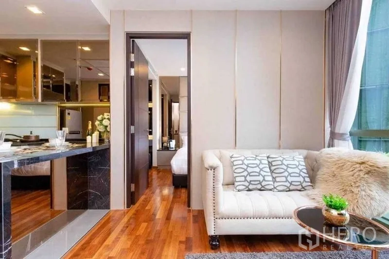 Condominium for sale in Ratchathewi, Bangkok - Cozy living space with tufted sofa, marble breakfast bar, and sliding door to the bedroom.