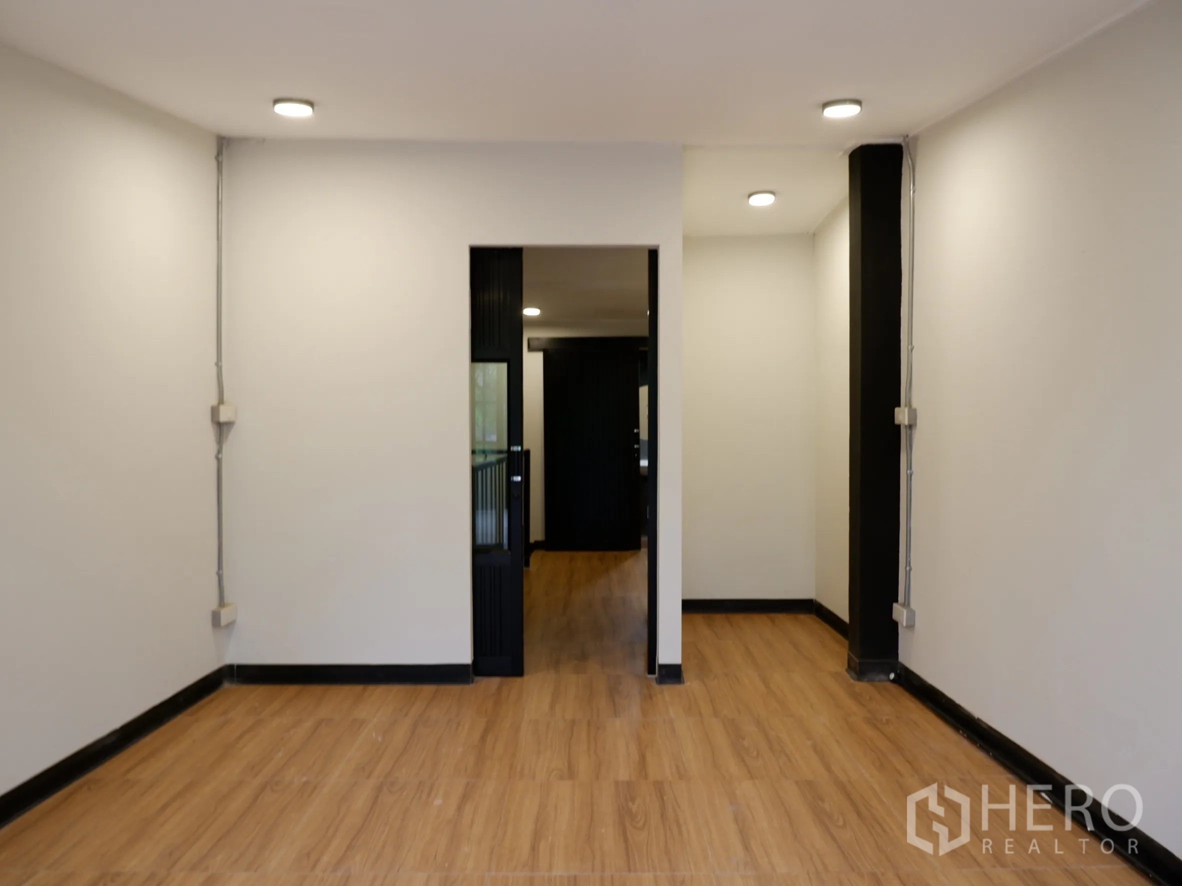 สำนักงานที่บ้าน ขายในBang Rak, Bangkok - ห้องทำงานสว่าง ผนังสีขาว ไฟฝ้า และประตูเชื่อมสู่พื้นที่บริการ พื้นไม้