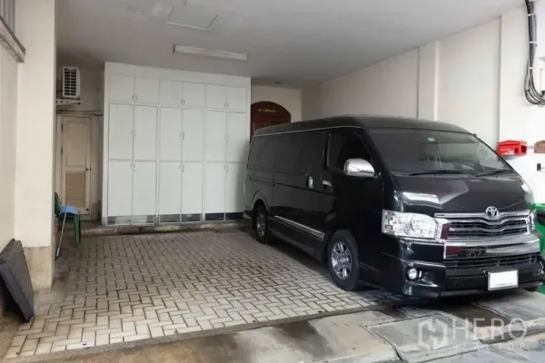 联排别墅 出售 - 有顶车位，铺设砖块地面，白色收纳柜与一辆厢式车。