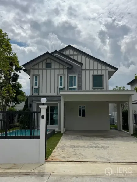 Detached House for rent in Bang Phli, Samut Prakan - Front facade with gated entrance, carport and side pool of the detached home.