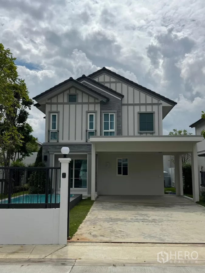 Detached House for rent in Bang Phli, Samut Prakan - Front facade with gated entrance, carport and side pool of the detached home.