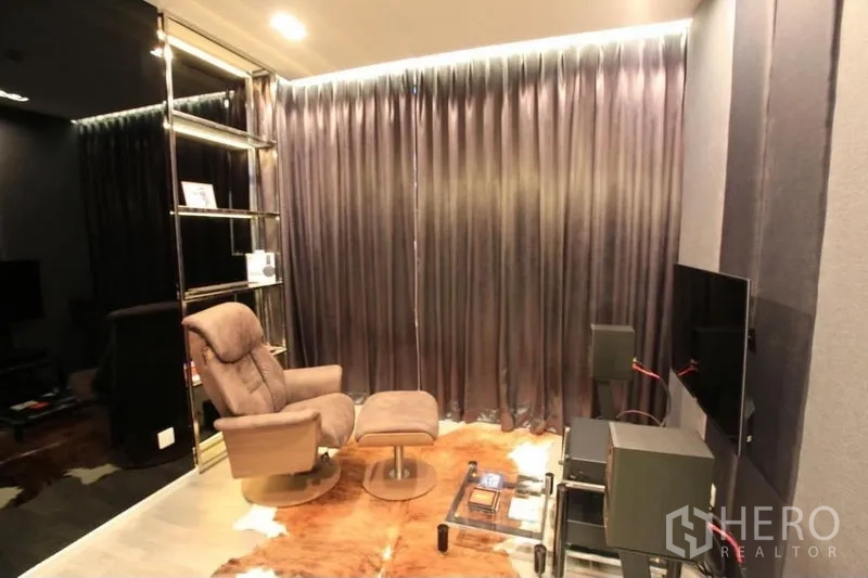 Condominium for rent or sale in Watthana, Bangkok - Cozy media room with recliner, ottoman and wall-mounted TV.
