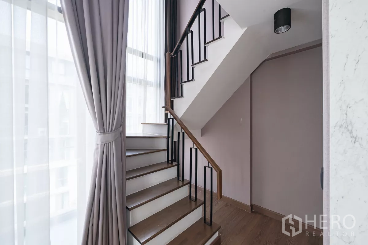 คอนโด ให้เช่าหรือขายในPhra Khanong, Bangkok - บันไดภายในราวเหล็กสีดำข้างหน้าต่างสูงและผ้าม่านเฉดเทา