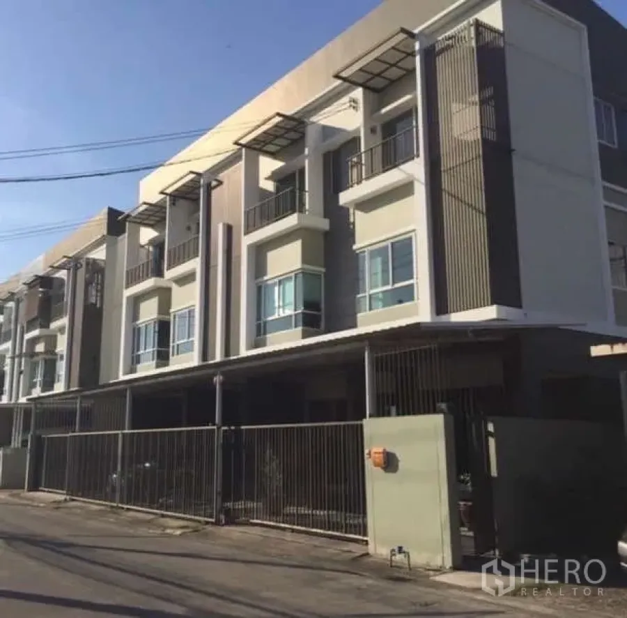 Townhouse for rent in Saphan Sung, Bangkok - Front elevation of a gated three-storey townhouse building with balconies.