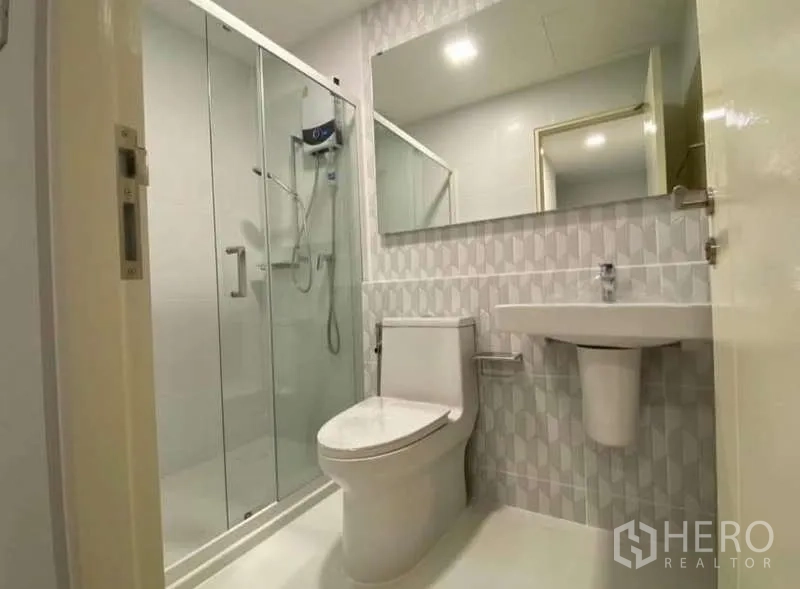 Townhouse for rent in Bang Phli, Samut Prakan - Sleek bathroom with patterned tiles, glass shower and wide vanity mirror.