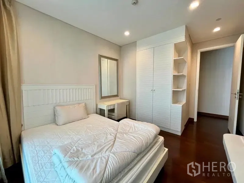 Condominium for rent in Watthana, Bangkok - Second bedroom with white bed, wardrobe, dressing table, and shelving.