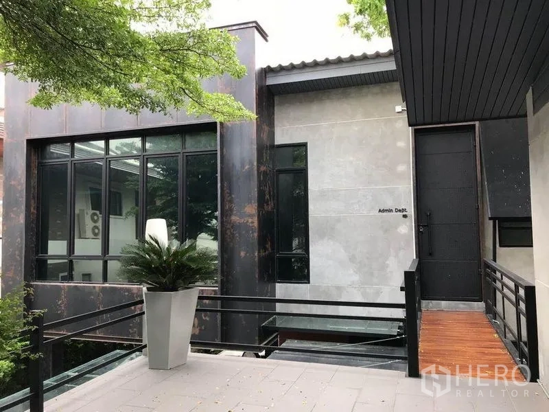 Office Space for rent in Bang Kapi, Bangkok - Exterior walkway leading to an admin building with large windows and planters.