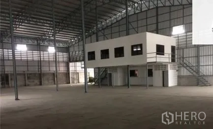 Warehouse for rent in Phra Samut Chedi, Samut Prakan - High-ceiling warehouse interior with steel frame and a white mezzanine office block.