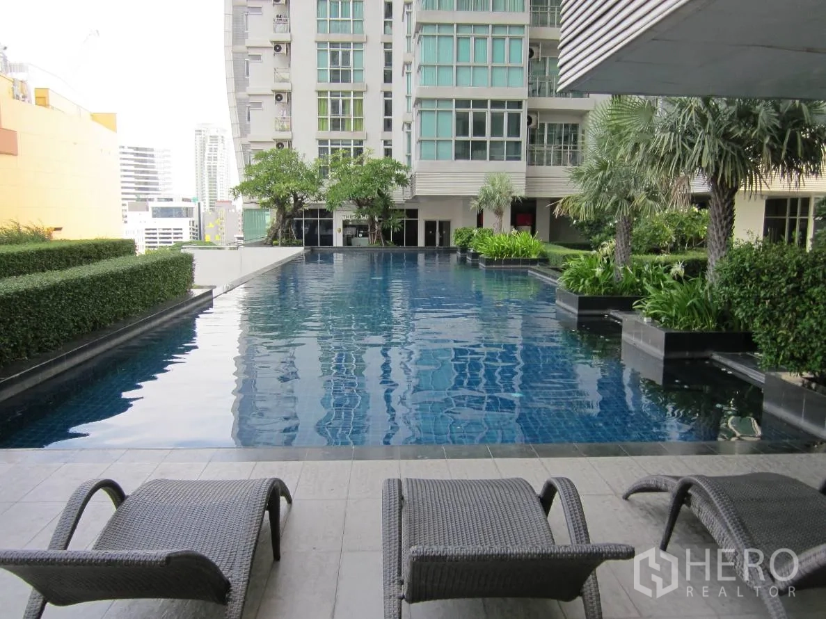 Condominium for rent or sale in Khlong Toei, Bangkok - Condominium facilities with landscaped outdoor swimming pool, sun loungers and city backdrop.