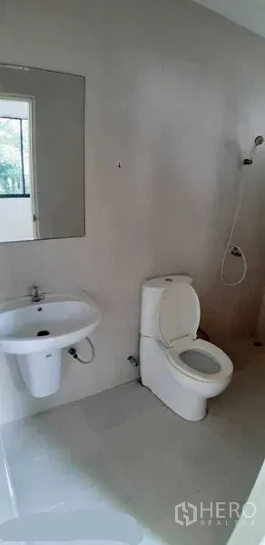 Detached House for rent in Prawet, Bangkok - Modern bathroom with toilet, wall mirror, basin and handheld shower.