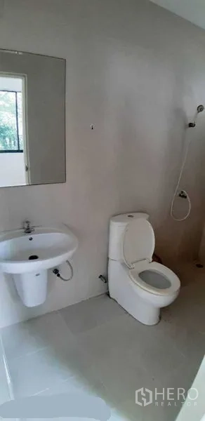 Detached House for rent in Prawet, Bangkok - Modern bathroom with toilet, wall mirror, basin and handheld shower.