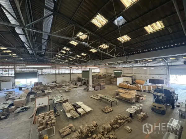 Factory for sale in Khlong Toei, Bangkok - Open factory area with stacked materials and a forklift near the loading bay