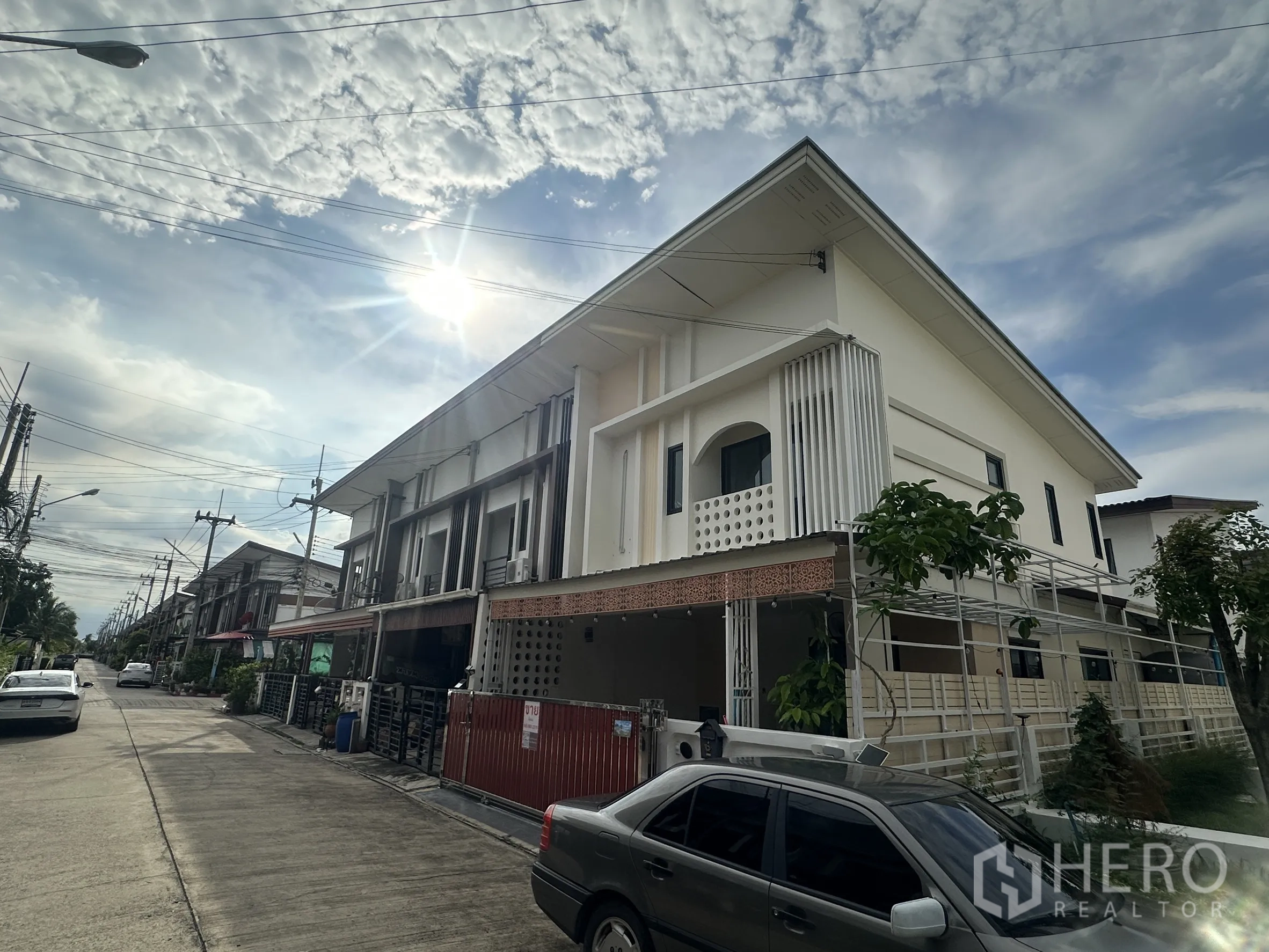 联排别墅 for sale in Lam Luk Ka, Pathum Thani - 晴空下住宅街景中的现代两层联排别墅外观。
