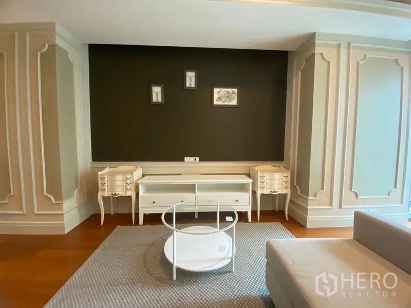 คอนโด ให้เช่าในKhlong Toei, Bangkok - ห้องนั่งเล่นคอนโดสไตล์คลาสสิก ผนังบัวกรอบ ทีวีคอนโซลสีขาว และโต๊ะกลางทรงกลม