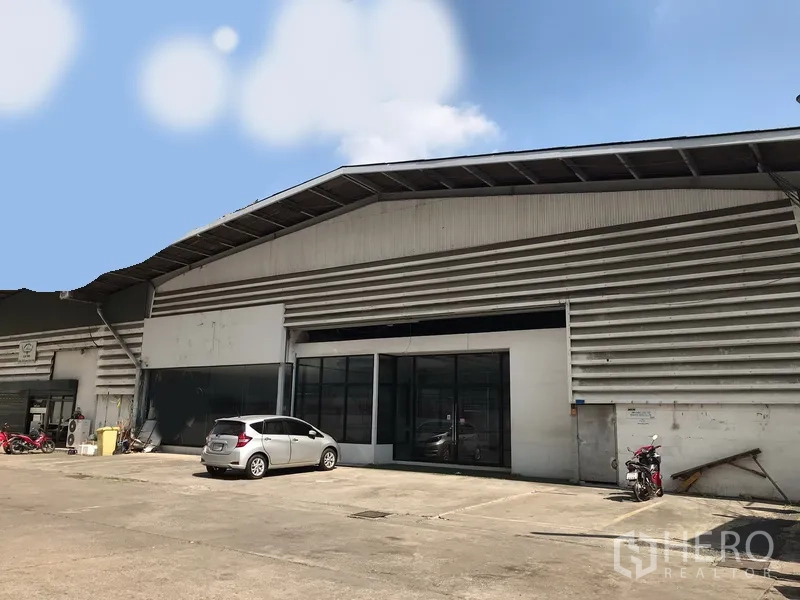 Warehouse for rent in Khlong Toei, Bangkok - Wide exterior of a corrugated metal warehouse with sliding glass entry and loading access in central Bangkok.