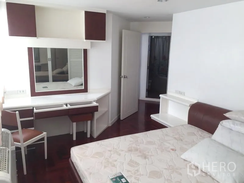 Condominium for rent in Watthana, Bangkok - Bright bedroom with built-in vanity desk, wardrobe, and wood floors.