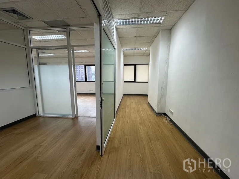 办公空间 出租在Watthana, Bangkok - 走廊通向带窗工作区，可见城市景观与玻璃隔断。