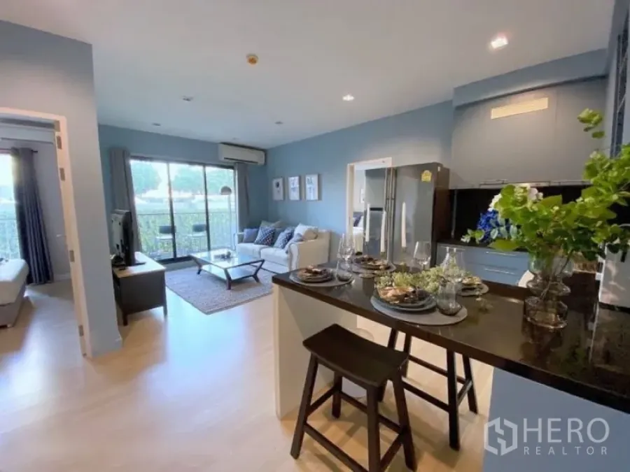 Condominium for rent or sale in Sathon, Bangkok - Open-plan living area with sofa, balcony doors and a kitchen island in a modern Sathon condo.