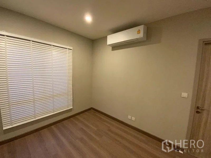 联排别墅 出租在Prawet, Bangkok - 次卧木地板，中性色墙面与空调。