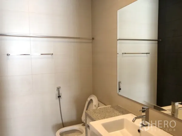 คอนโด ให้เช่าหรือขายในKhlong Toei, Bangkok - ห้องน้ำโทนสว่างพร้อมอ่างล้างหน้า กระจกบานใหญ่ โถสุขภัณฑ์ และสายชำระ