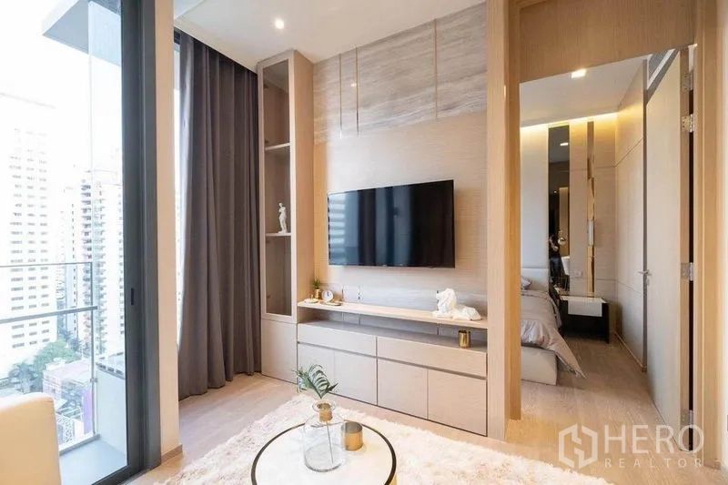 Condominium for rent in Watthana, Bangkok - TV feature wall facing balcony, with doorway leading to the bedroom.