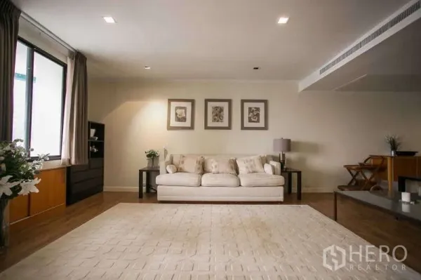 คอนโด ให้เช่าหรือขายในWatthana, Bangkok - ห้องนั่งเล่นสว่าง โซฟาสีครีม พรมผืนใหญ่ และภาพติดผนัง พื้นไม้