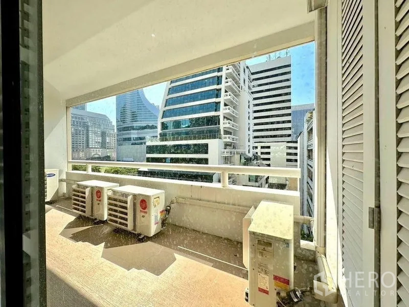 Condominium for rent - Covered balcony with city skyline outlook and external air-conditioning units.