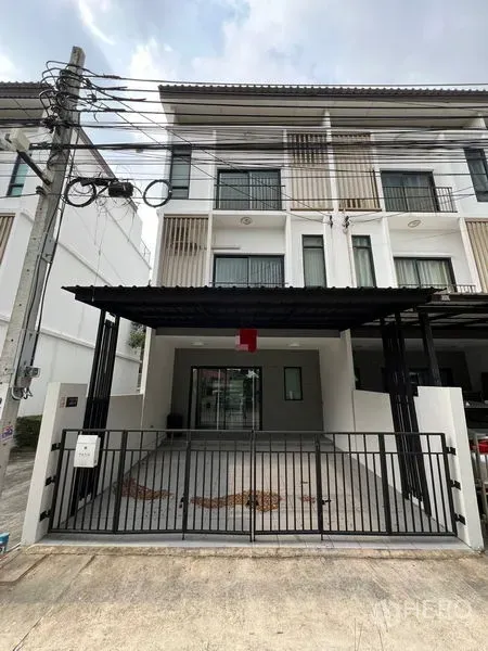 Townhouse for rent in Bang Kapi, Bangkok - Three-storey modern townhouse facade with gated carport and awning in Bang Kapi.