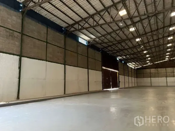 工厂 出租在Bang Pakong, Chachoengsao - 仓库侧边区域，超大推拉门、保温墙板与平整混凝土地面。