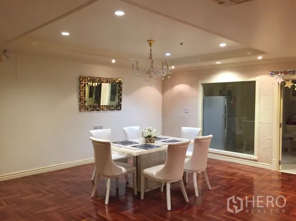 Condominium for rent in Watthana, Bangkok - Elegant dining space featuring a six-seat table under a crystal chandelier beside a glass window to the kitchen.