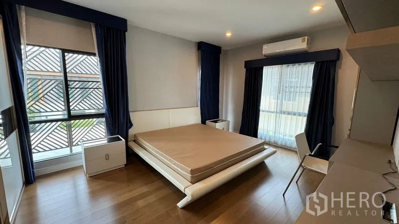 Detached House for rent in Prawet, Bangkok - Corner bedroom with wood floors, dark curtains and air conditioner.