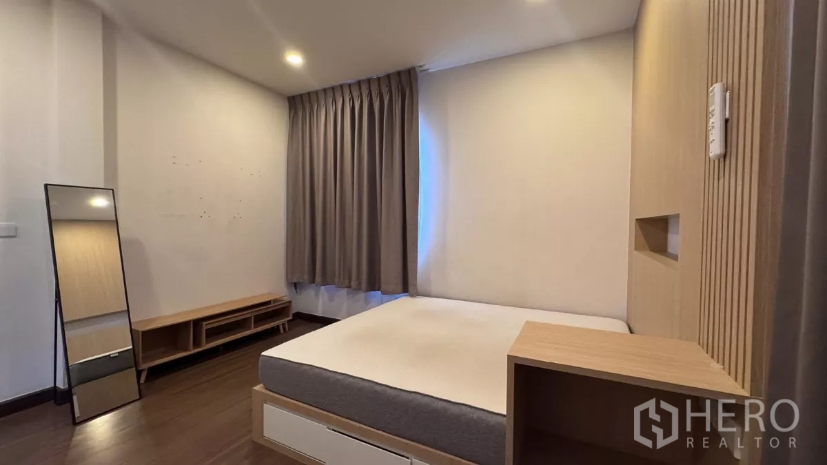 บ้าน ให้เช่าหรือขายในSaphan Sung, Bangkok - ห้องนอนบรรยากาศอบอุ่น เตียงแพลตฟอร์ม ผนังหัวเตียงลายไม้ และผ้าม่านสีเทาหนาทึบ.