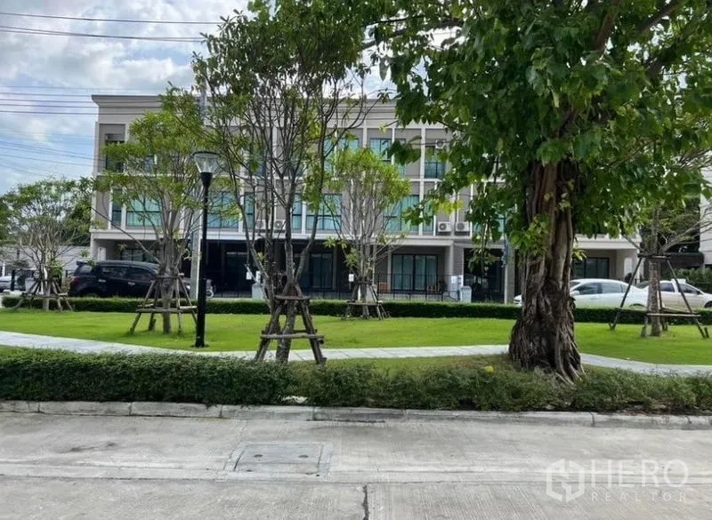 Townhouse for rent - Lush communal park with trees and pathway facing a row of townhouses.