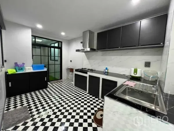 独立式住宅 出售在Khan Na Yao, Bangkok - 宽敞厨房，黑色橱柜、仿石墙面、抽油烟机与黑白棋盘地砖。