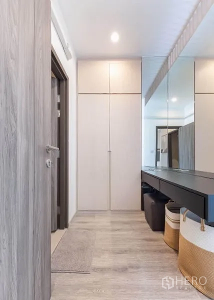 Condominium for rent in Bang Na, Bangkok - Wardrobe corridor with mirrored wall and sleek black vanity counter.