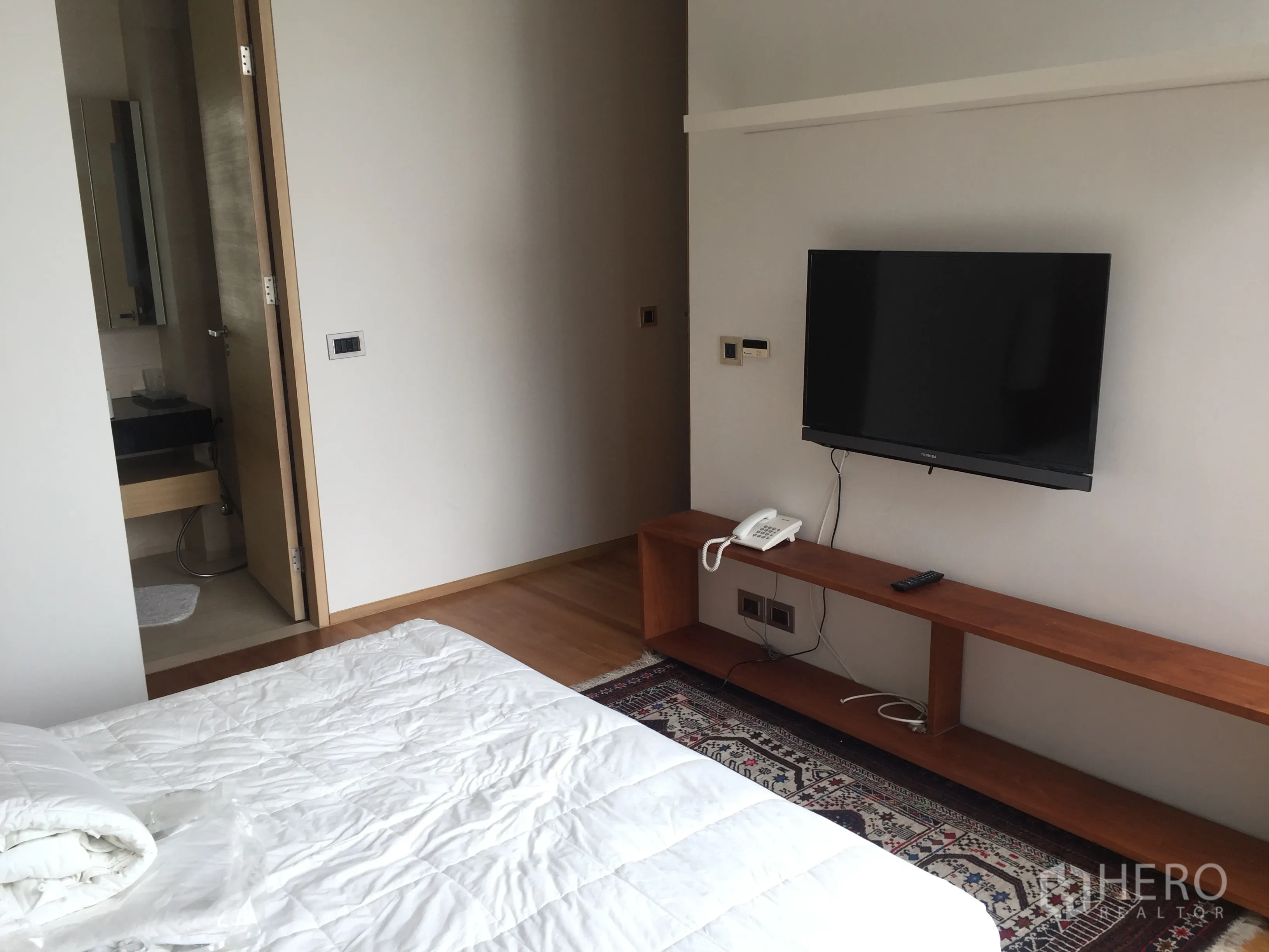 公寓 出租在Bang Rak, Bangkok - 卧室配壁挂电视、长木置物台，并有门通往套内卫浴。