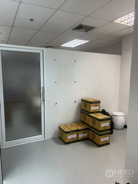 办公空间 出租 - 带磨砂玻璃门的角落空间，白墙，堆放的纸箱。