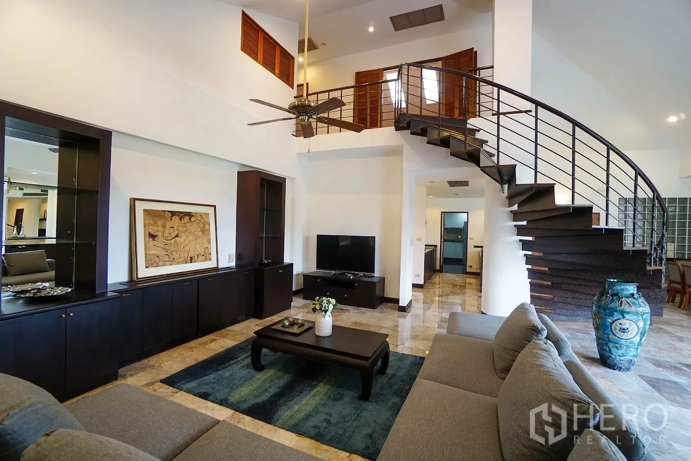 อพาร์ทเมนท์ for rent in Watthana, Bangkok - ห้องนั่งเล่นแบบดูเพล็กซ์มีบันไดโค้ง พัดลมเพดาน โซฟาตัวแอล ตู้บิลท์อิน และชั้นวางทีวี