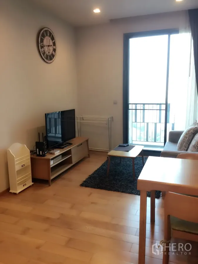 คอนโด ให้เช่าในKhlong Toei, Bangkok - ห้องนั่งเล่นสว่าง พื้นไม้ ชั้นวางทีวี โซฟา และประตูกระจกออกสู่ระเบียง ใกล้ BTS ทองหล่อ