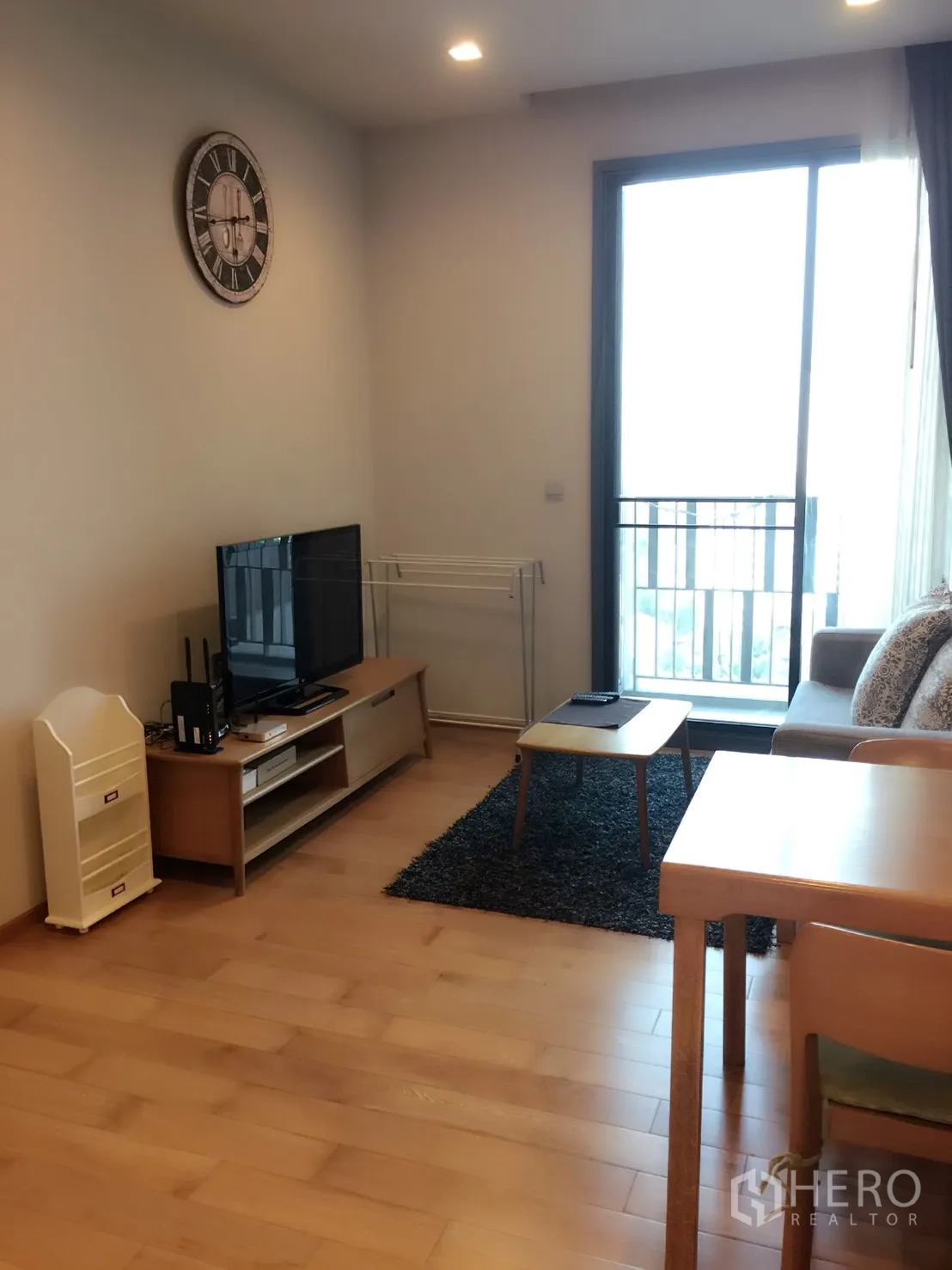 คอนโด ให้เช่าในKhlong Toei, Bangkok - ห้องนั่งเล่นสว่าง พื้นไม้ ชั้นวางทีวี โซฟา และประตูกระจกออกสู่ระเบียง ใกล้ BTS ทองหล่อ