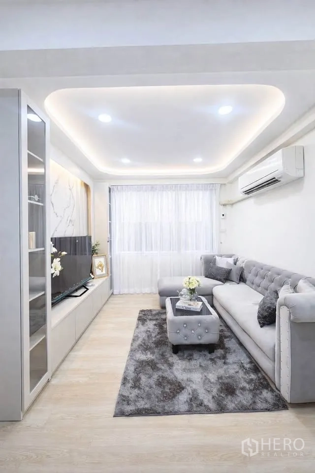 独栋房屋 for rent in Huai Khwang, Bangkok - 客厅设L形沙发、电视柜、嵌入式顶灯与地毯。