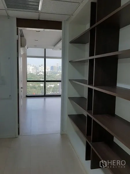 办公空间 出租在Bang Rak, Bangkok - 带开放式层架的走道，通往采光明亮的大窗办公室。