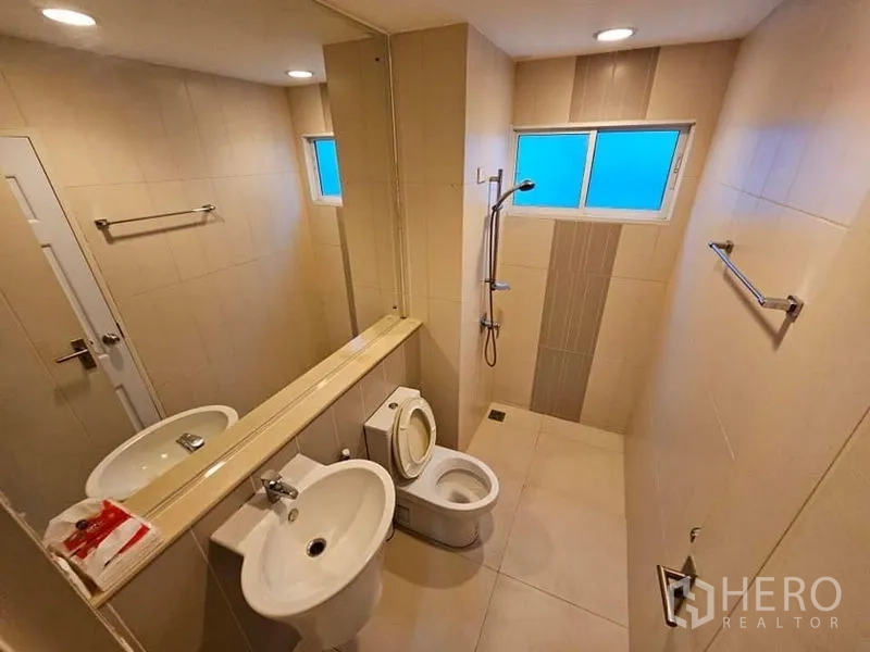 Townhouse for rent in Wang Thonglang, Bangkok - Second bathroom with large mirror, shower area, frosted windows, and towel rails.