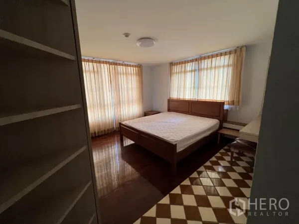 公寓 出租在Watthana, Bangkok - 明亮卧室，木床，大窗配米色窗帘，木地板与棋盘格瓷砖边。