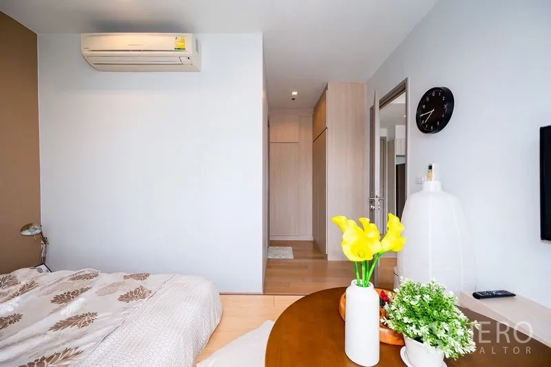 Condominium for rent or sale in Watthana, Bangkok - Bedroom view toward hallway with built-in wardrobes, air conditioner, and decor clock.