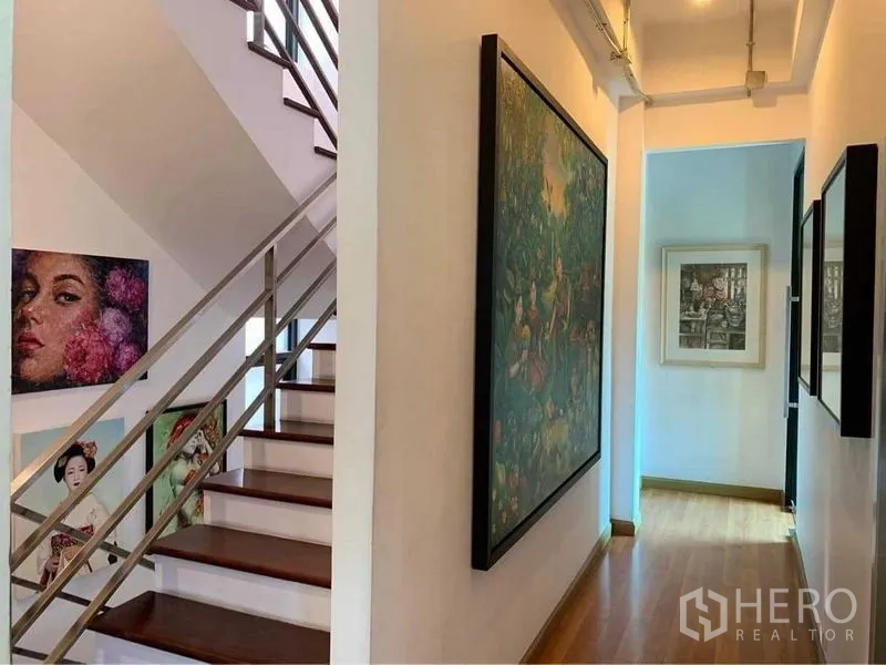 带办公室的家 出售在Wang Thonglang, Bangkok - 艺术走廊与木楼梯，不锈钢扶手，白墙挂满画作