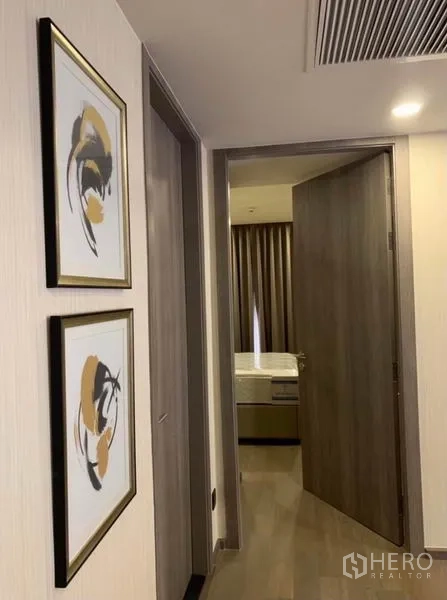 คอนโด ให้เช่าในPathum Wan, Bangkok - โถงทางเดินประดับกรอบรูป นำไปสู่ห้องนอนที่มีผ้าม่านสีเข้ม