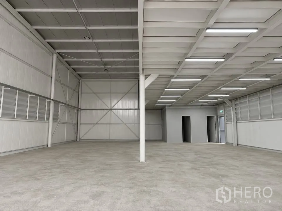 Warehouse for rent in Bang Na, Bangkok - Spacious warehouse floor with linear lighting and rear service rooms.