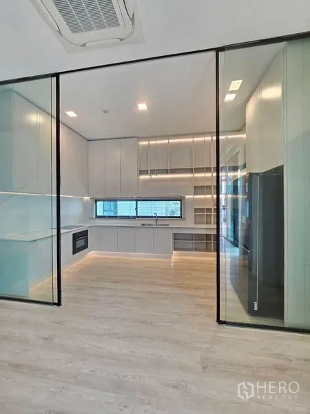 Detached House for rent - Enclosed modern kitchen behind glass sliding doors with full cabinetry and window.