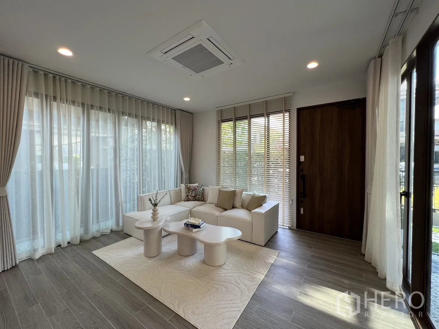 Detached House for rent or sale in Bang Kapi, Bangkok - Spacious lounge with full-height windows, wood door and recessed lighting.